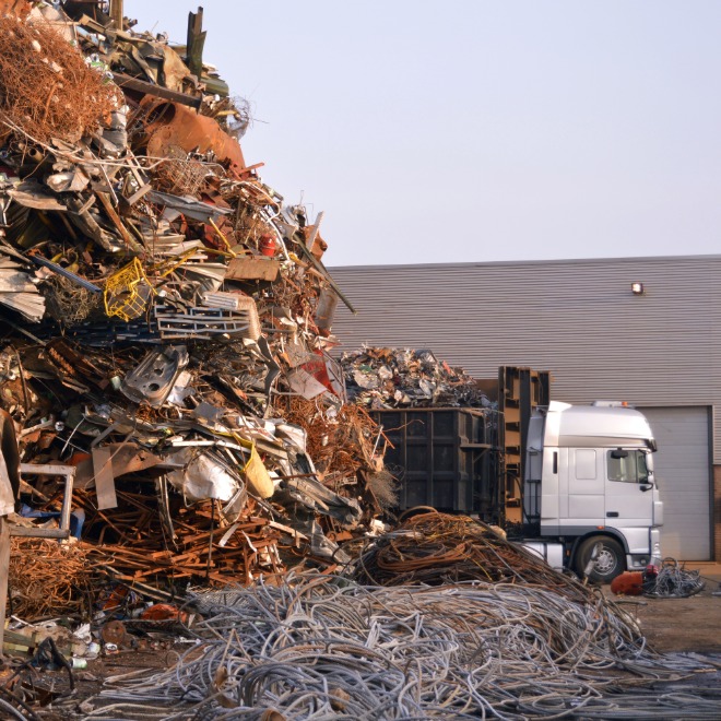 Garbage truck beside debris at a scrap yard