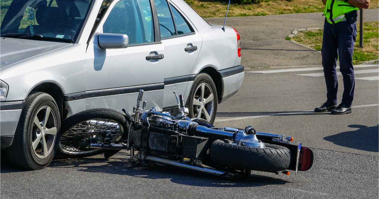 Motorcycle down beside a sedan with an officer nearby